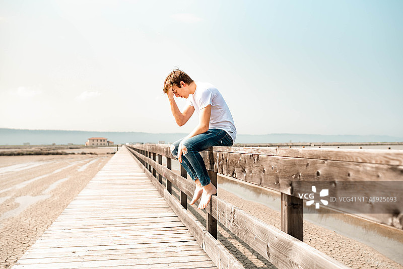 年轻人坐在木栅栏上图片素材