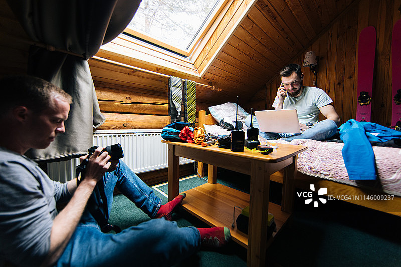登山者在山间小屋里使用电脑和相机设备图片素材