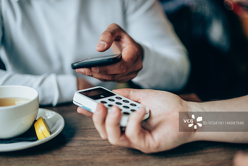 在咖啡馆用智能手机非接触式支付的男人图片素材