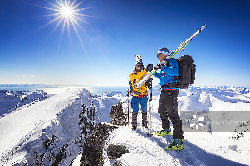 在挪威罗弗敦山峰上握手的两位伙伴图片素材