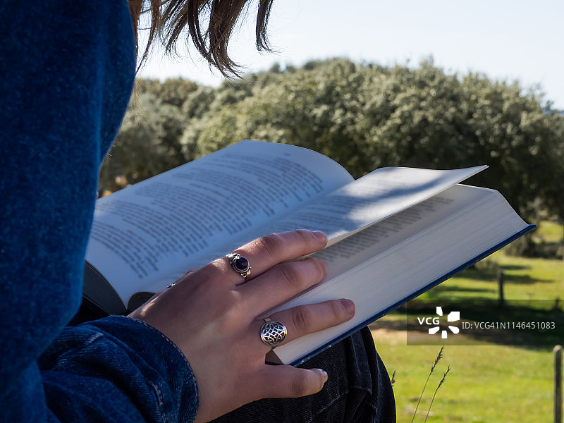 在樹旁看書的青少年女性图片素材