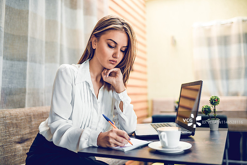 女会计在喝咖啡时在纸上记录数据图片素材
