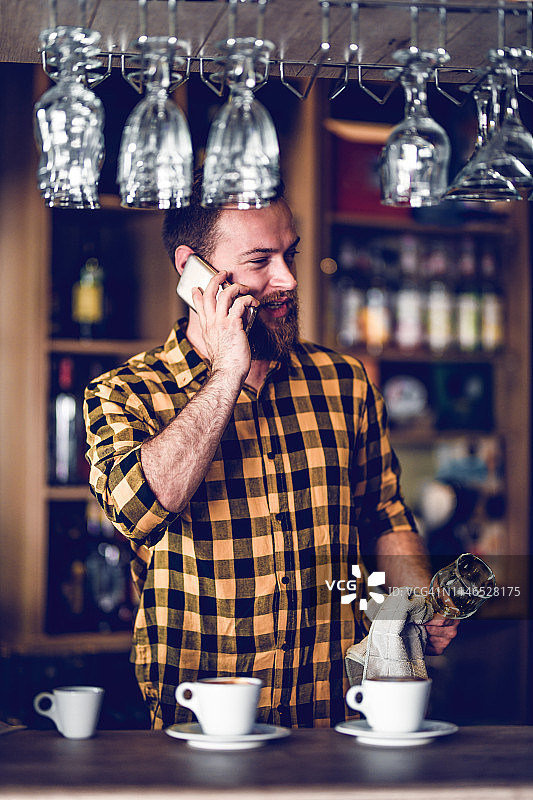 英俊的男调酒师在做咖啡和打电话图片素材