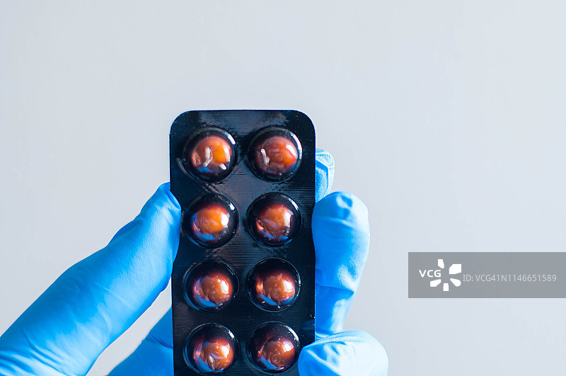 戴蓝色手套的年轻人拿着一盒药图片素材