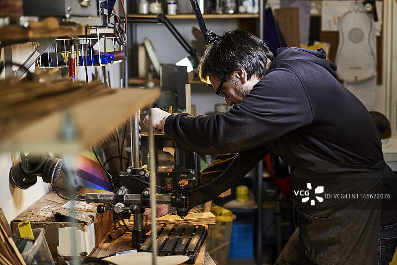 乐器制造商在他的工作室使用钻床图片素材