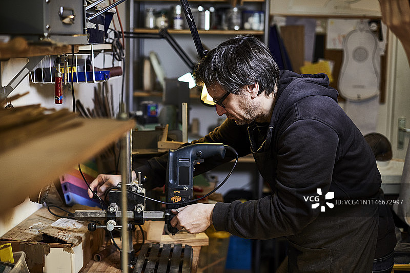 乐器制造商在他的工作室使用钻床图片素材