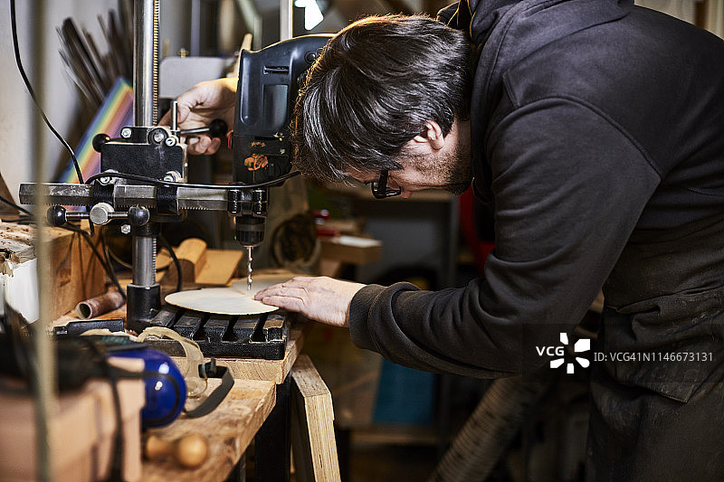 乐器制造商在他的工作室使用钻床图片素材
