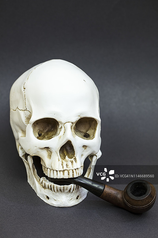 叼着烟斗的人类头骨。吸烟有害健康图片素材