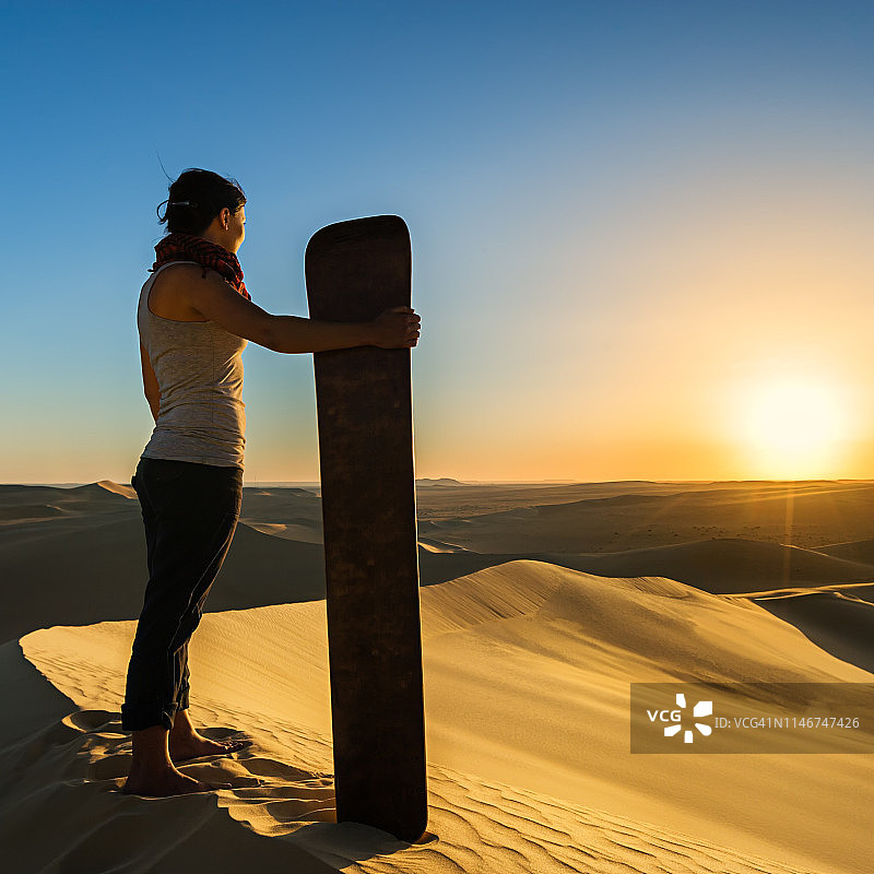 年轻女人在非洲撒哈拉沙漠日落时分玩沙图片素材