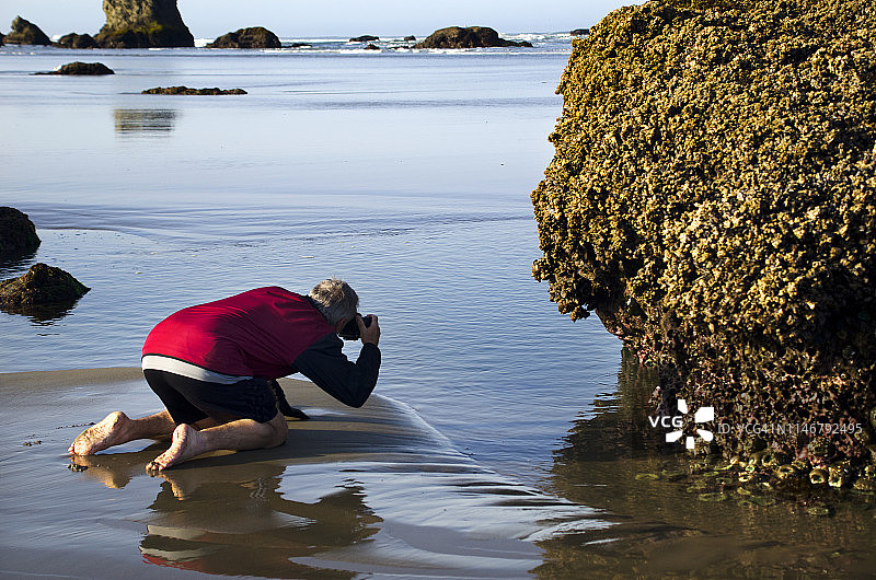 年长的男人拍摄海滩潮汐池图片素材
