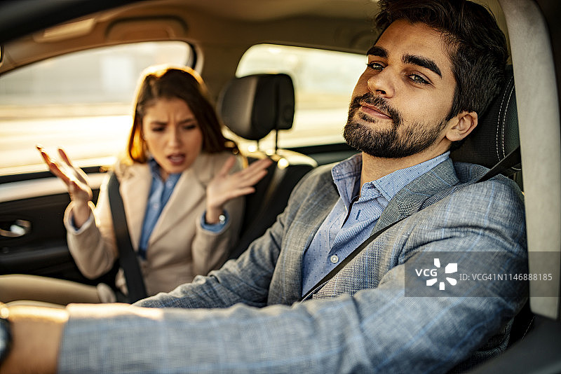 男人开车，女乘客在一旁忙碌图片素材