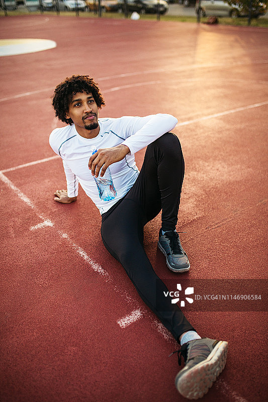 年轻男子锻炼后坐在球场上图片素材