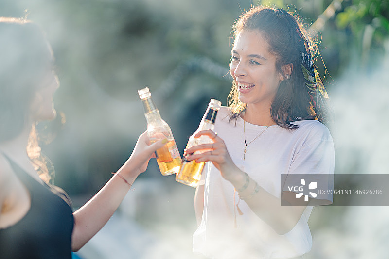 两名女子在家庭派对上用啤酒碰杯图片素材