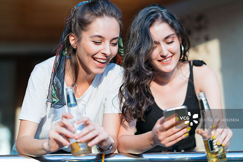 两个女人喝啤酒玩手机图片素材
