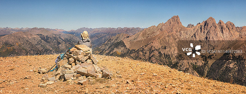 徒步者在山顶石堆旁休息全景图图片素材