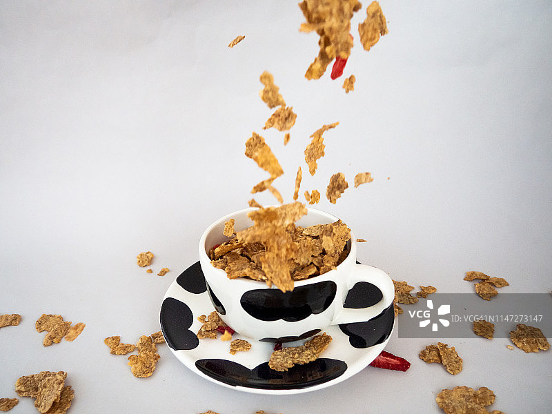 早餐时掉入黑白碗中的大量早餐麦片和红色水果图片素材