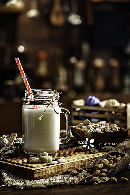 老式乡村厨房中装在玻璃杯和罐子里的非乳制杏仁奶和坚果图片素材