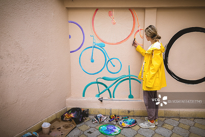 快乐的女艺术家在后院画壁画图片素材