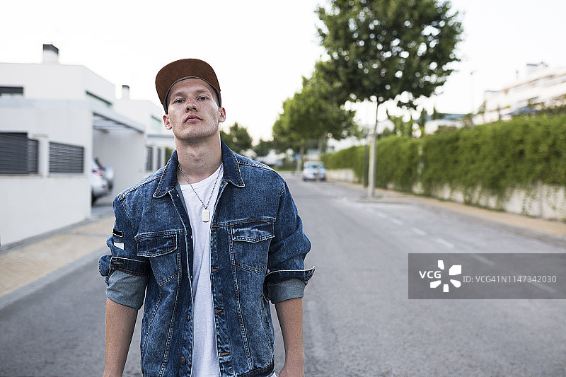 穿牛仔夹克站在街上的年轻男人肖像图片素材