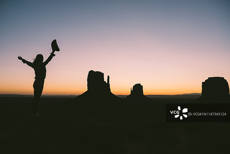 美国犹他州纪念碑谷：戴牛仔帽的女子剪影，欣赏日出图片素材