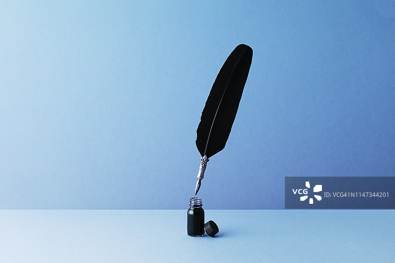 蓝色背景上的羽毛笔和墨水池图片素材