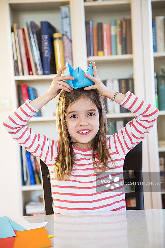 在家戴自制纸帽的微笑女孩肖像图片素材