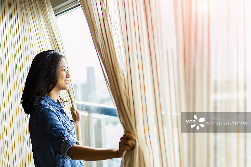美丽的女人拉开窗帘向外看图片素材