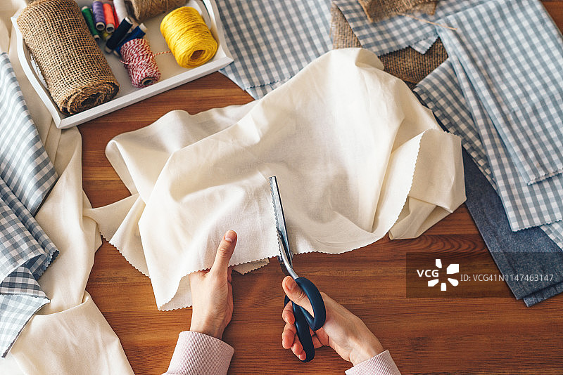 用粉红剪刀剪布料的女人图片素材