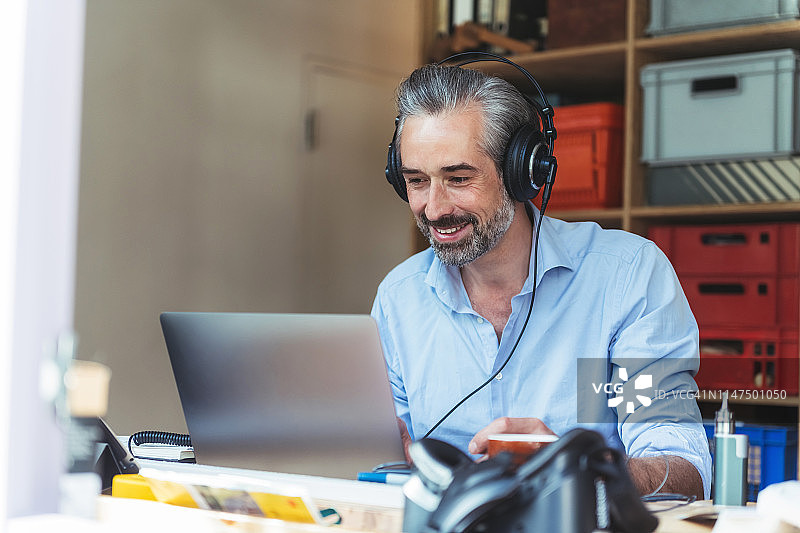 戴耳机在家用笔记本电脑工作的创意男人图片素材