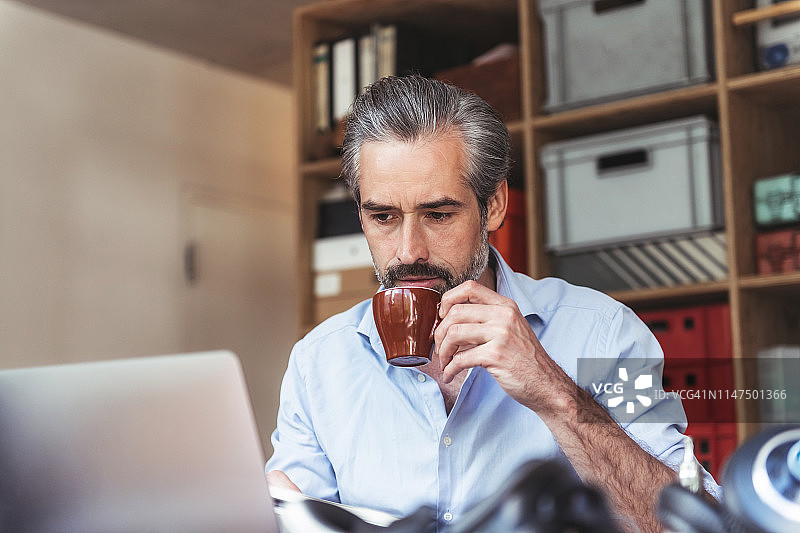 留着胡子的商人工作时喝咖啡图片素材
