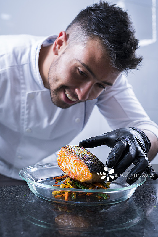 职业厨师在透明盘中摆盘三文鱼蔬菜图片素材