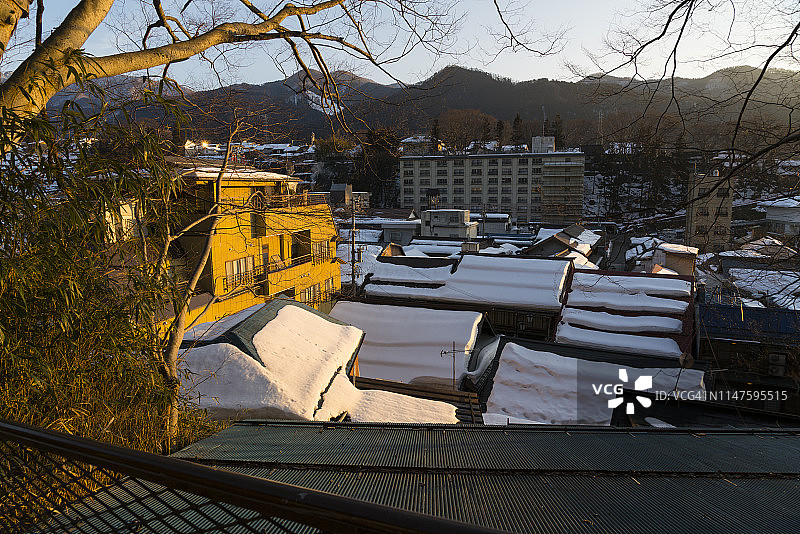 2019年2月18日，长野县山之内町涉温泉（涉温泉）镇，夕阳下白雪皑皑的拥挤屋顶图片素材