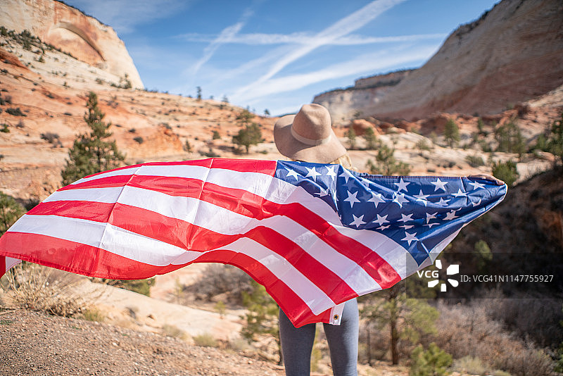 女孩在美国旅行，手持美国国旗欣赏自然风光图片素材
