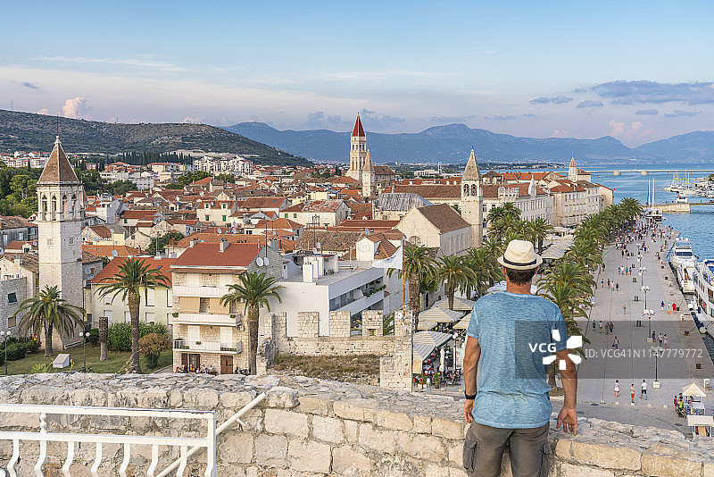 戴着帽子，在克罗地亚Split-Dalmatia县Trogir的Karmelengo城堡欣赏老城的男人图片素材