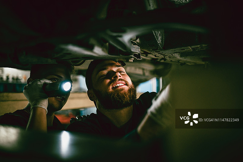 学徒为汽车修理工提供照明图片素材
