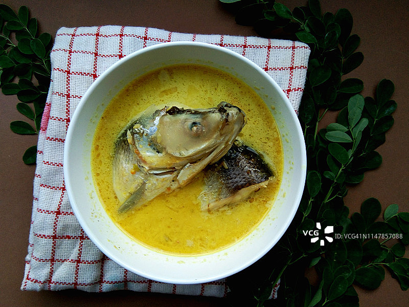 白色碗里的黄色椰奶牛奶鱼，背景是乡村棕色木纹图片素材