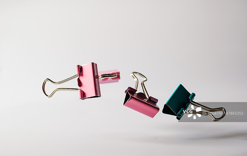 用高速拍摄的、在半空中跳跃的金属文件剪辑，白色背景图片素材