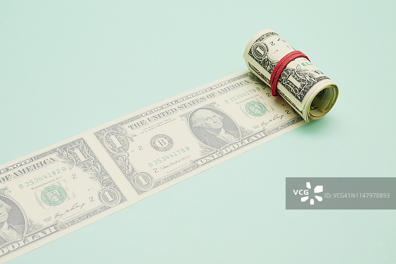 一卷美元钞票在蓝绿色背景上图片素材