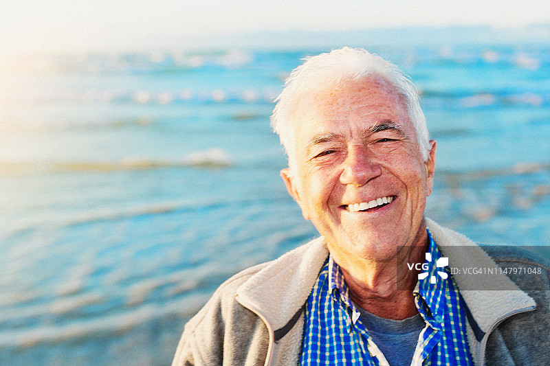 笑容满面的年长男士站在阳光明媚的海边图片素材