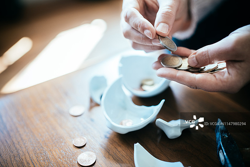 从破碎的存钱罐中数硬币图片素材