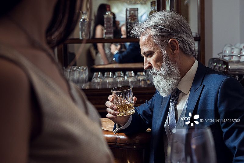 穿着优雅的老年男人坐在酒吧里图片素材