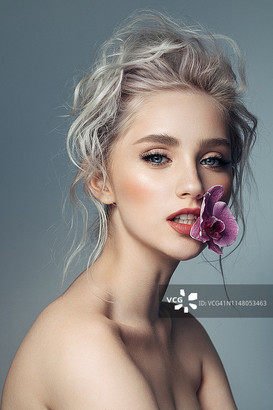 年轻漂亮的女人嘴里含着兰花图片素材