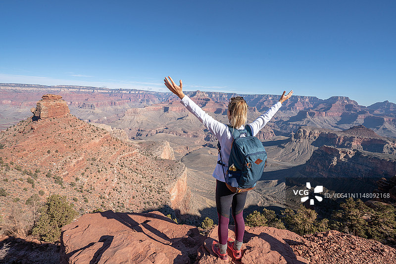 年轻女子站在峡谷顶端，拥抱生活与自然，张开双臂，享受徒步旅行，美国风光图片素材