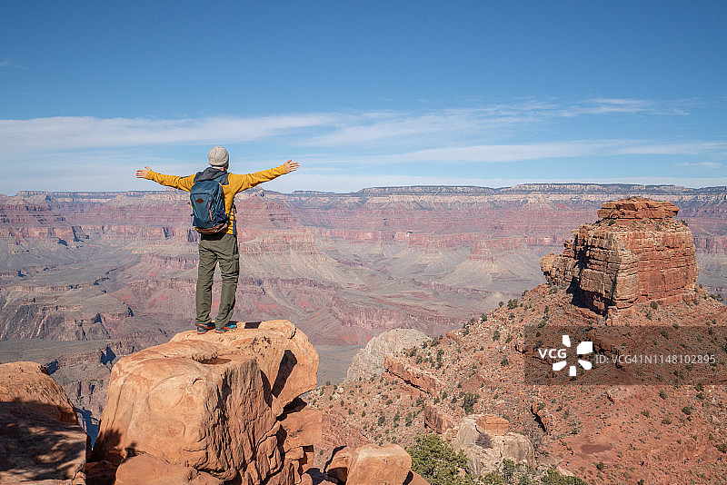 年轻男子拥抱生活，站在峡谷顶端，张开双臂，享受徒步旅行，美国风光图片素材