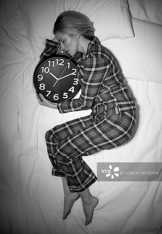 女人在床上睡觉，旁边有闹钟图片素材