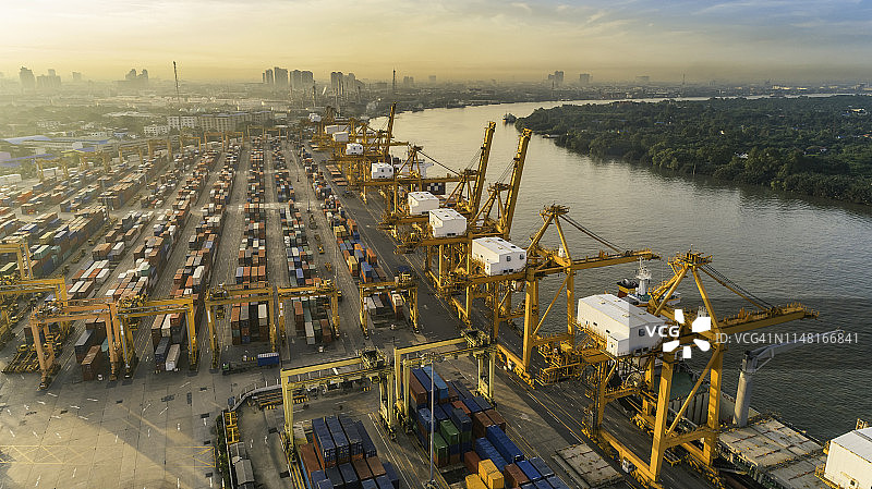 码头集装箱船在岸边通过桥式起重机装卸货物的鸟瞰图，用于物流、进出口、运输图片素材