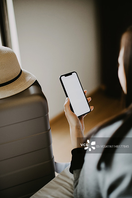 年轻女游客在酒店房间用手机进行视频通话图片素材