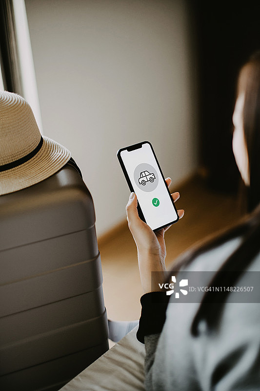 年轻女子在酒店房间用手机预订租车服务图片素材