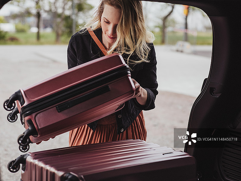 女人将行李袋装入车内，准备旅行图片素材