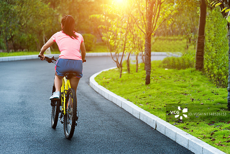 年轻亚洲女性在公园骑自行车图片素材